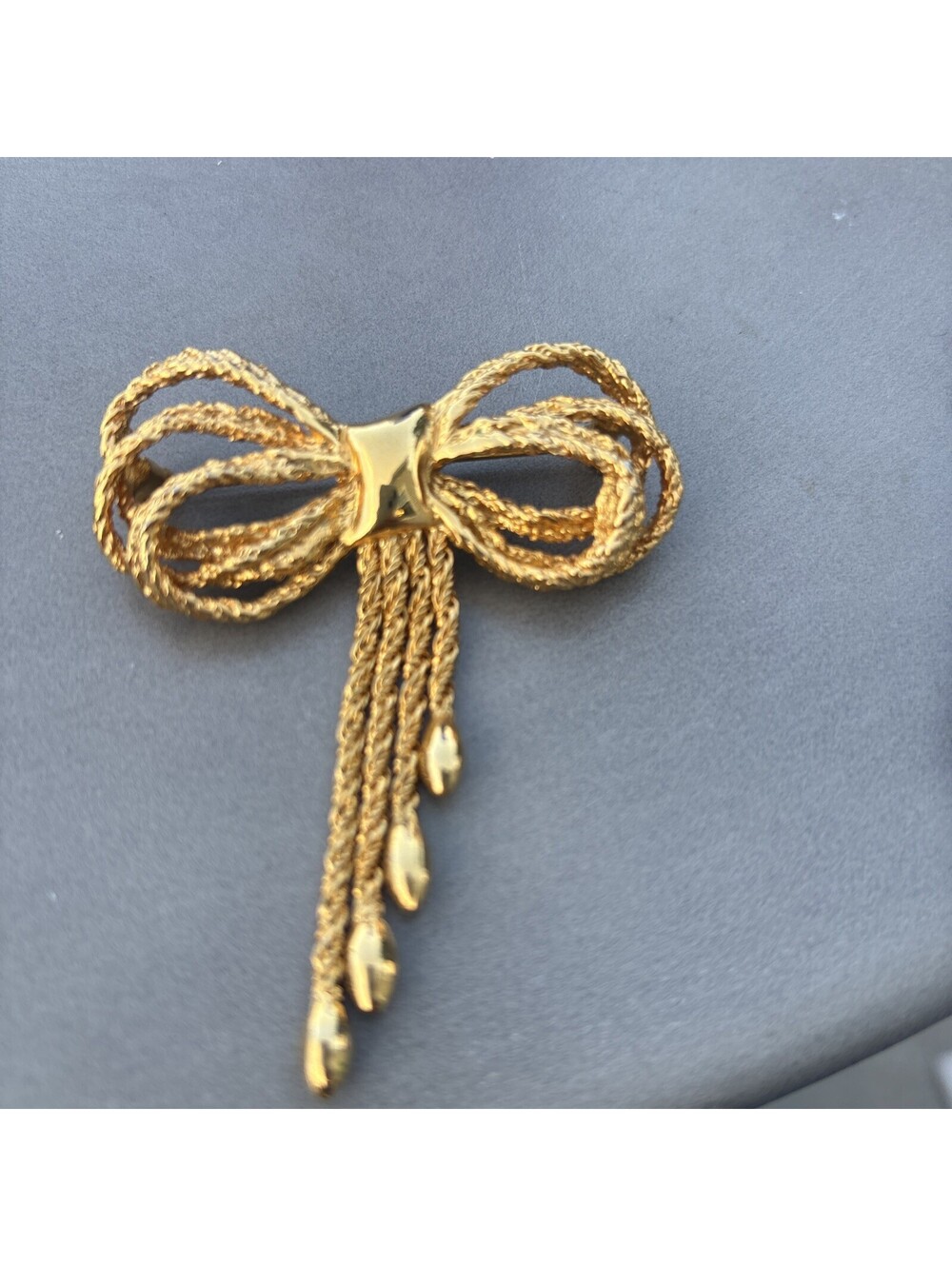 A vintage gold‑tone bow brooch featuring intricate braided metalwork